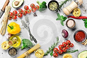 Frame of organic food. Fresh raw vegetables with spices, basil and rosemary on a gray stone background.