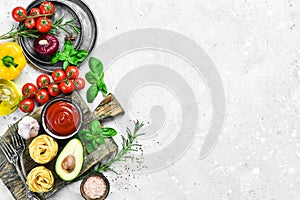 Frame of organic food. Fresh raw vegetables with spices, basil and rosemary on a gray stone background.