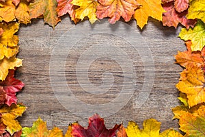 Frame out of colourful autumn leaves on wooden background