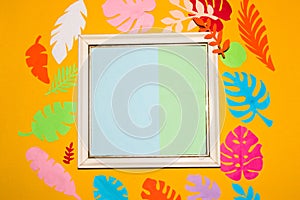 frame with pastel blue-green copy space around the frame yellow background with colorful jungle leaves