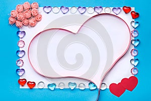 In a frame of pebbles on a blue background, a ribbon in the shape of a heart