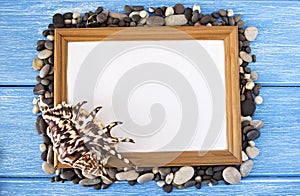 Frame of pebbles and shells on a blue wooden background