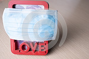 a frame with a photo of a young couple in love is covered with a medical mask. covid prevents people from loving