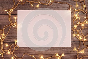 A frame of pine branches and Christmas decorations and A4 sheet of white paper on a wooden table. Holidays christmas background.