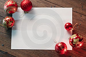 A frame of pine branches and Christmas decorations and A4 sheet of white paper on a wooden table. Holidays christmas background.