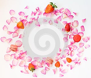 A frame with pink rose petals, sugar stars, strawberries, french