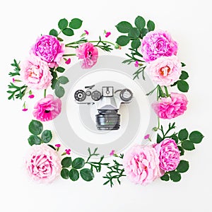 Frame of pink roses and old retro camera on white background. Floral lifestyle composition. Flat lay, top view.