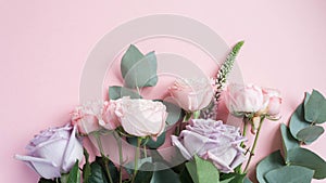Frame of purple and pink roses, white Lisianthus and different flowers on pink background