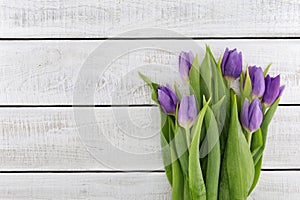 Frame of purpleviolet tulips on white rustic wooden background
