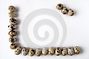 frame of quail eggs on perimeter of two sides on white background. Three eggs in the corner.