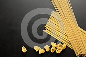 Frame from raw organic macaroni shells and spaghetti on black