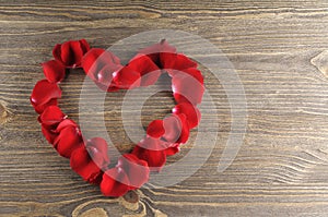 Frame of red rose petals heart on a wood background.
