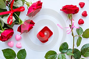 Frame of red roses, leaves, hearts and wedding rings on a white background