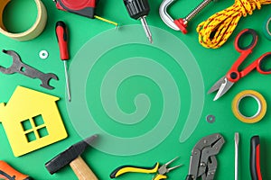 Frame of repair tools and house  on green background, flat lay. Space for text