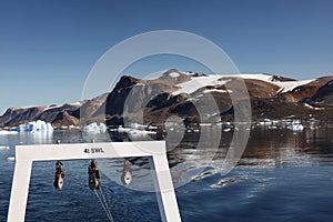 The A-frame of a research vessel is seen as it navigates around icebergs in a fjord in northwest Greenland