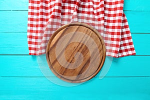 Frame of round cutting board and red plaid tablecloth. Blue wooden background in the cafe. Top view