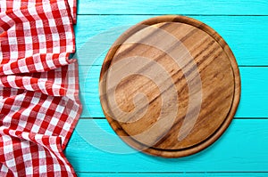 Frame of round cutting board and red plaid tablecloth. Blue wooden background in the restaurant. Top view