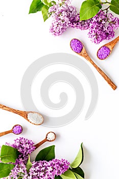 Frame of sea bath salt and purple flowers, top view