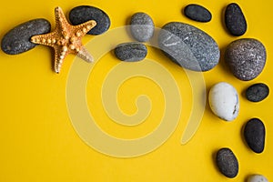 Frame from sea shell, star and stones, summer concept, copy space on yellow background