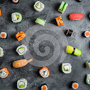 Frame with set of Japanese food on dark background. Sushi rolls, nigiri, raw salmon steak and avocado. Flat lay. Top view