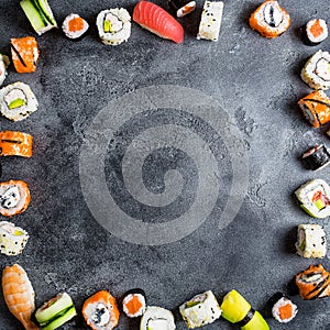 Frame with set of Japanese food on dark background. Sushi rolls, nigiri, raw salmon steak, rice and avocado. Flat lay. Top view