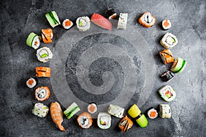 Frame with set of Japanese food on dark background. Sushi rolls, nigiri, salmon steak, rice and avocado. Flat lay. Top view