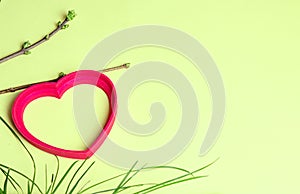 Frame in the shape of a heart. Spring shoots on branches and grass. Shot from above