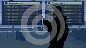 The frame shows an airport with a waiting room. A woman in silhouette looks at the scoreboard and checks the flights