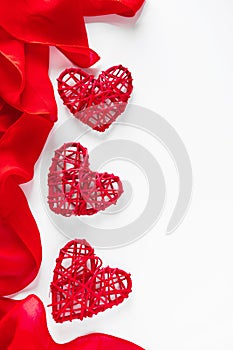 Frame of silk red ribbon and hearts on a white background