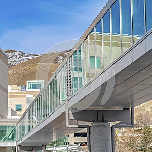 Frame Skybridge connected to a modern building with mountain and blue sky background