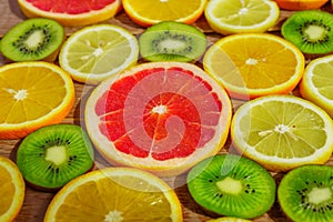 Frame with slices of oranges, lemons, kiwi, grapefruit pattern on wooden background. Copy space