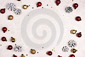 Frame of snow painted pine cones, balls and stars on a light marble background