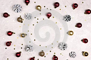 Frame of snow painted pine cones, balls and stars on a light marble background