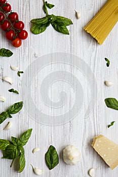 Frame with spaghetti and different ingredients for cooking italian pasta on a white wooden background,