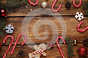 Frame of tasty candy canes and Christmas decor on wooden table, flat lay. Space for text