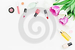 Frame with tulips flowers and cosmetics with perfume on white background. Top view. Flat lay. Copy space