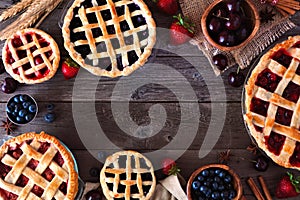 Frame of a variety of homemade fruit pies over a rustic wood background