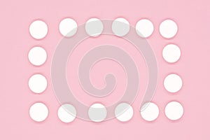 Frame of white tablets on a pink background