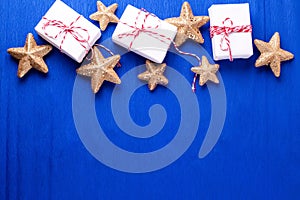 Frame  from wrapped boxes with presents  and golden decorative stars on blue paper  textured  background.