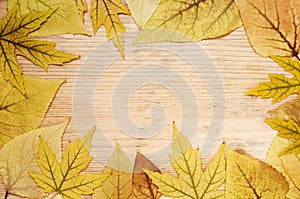 Frame of yellow autumn leaves on a wooden background. Autumn greeting card with leaves. Empty space for text.