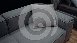 Frame zooms in on a gray couch with a gray pillow on a dark background. 4k video.