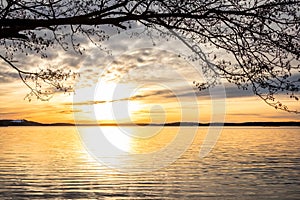 Framed beautiful orange winter landscape sunset over calm lake water with bright sun against sea horizon.