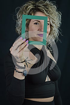 Framed Beauty - Portrait of a beautiful curly blonde woman holding a small frame in front of her face - concept for the uniqueness