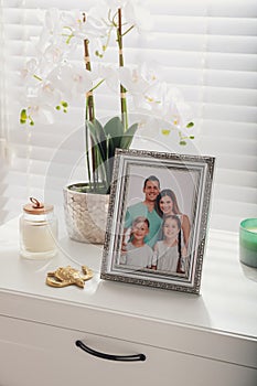 Framed family photo and flower on white drawer indoors