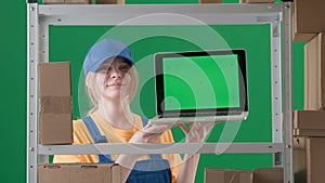 Framed on a green background, chromakey. Depicts a young woman in uniform and cap. Demonstrates a worker, in a warehouse