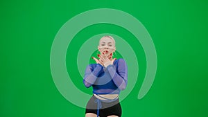 Framed on a green background, chromakey. A young, attractive woman is standing, she is dressed in bright, sexy clothes