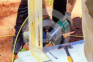 Framer uses an air nail hammer to install beams in a wooden frame photo