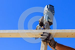 Framer uses an air nail hammer to install beams in a wooden frame photo