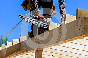 Framer worker installing beams using air nails hammer in a nailing wooden frame