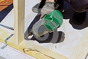Framer worker installing beams using air nails hammer in a nailing wooden frame photo